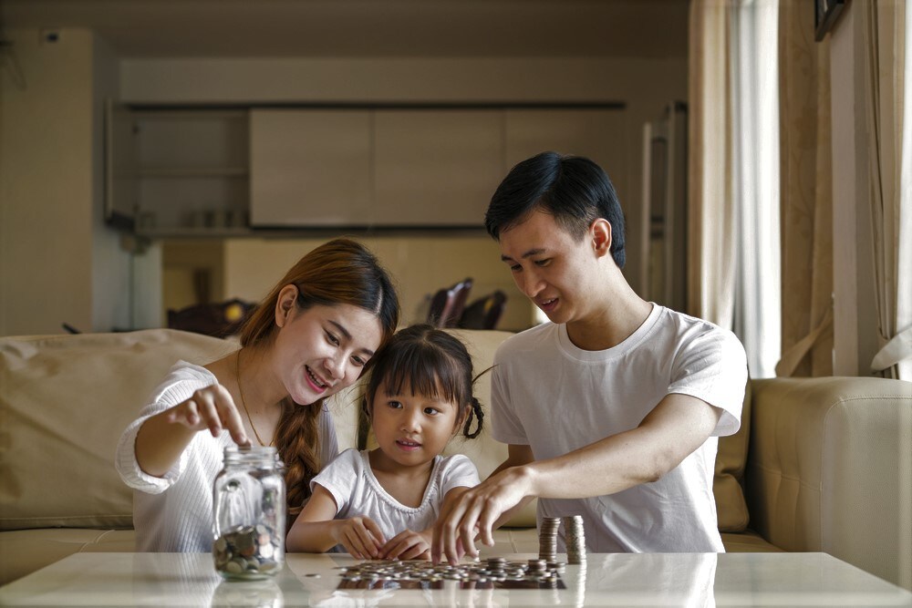 Family saving money putting coins into piggy bank